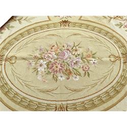 French Aubusson rug, central floral oval panel within a bay leaf band, the spandrels decorated with flowers and musical motifs