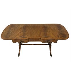 20th century mahogany sofa table, the drop leaf top over three frieze drawers, raised on four splayed supports, terminating in brass hairy paw castors 
