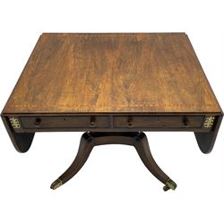 Regency rosewood and brass inlaid sofa table, drop leaf rectangular top with rounded corners, fitted with two drawers and two opposing false drawers, turned twin pillars on platform, splayed supports with foliate cast brass cups and castors