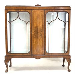 Early 20th century figured walnut display cabinet, the raised back over two tracery glazed doors enclosing two glass shelves, raised on shell carved cabriole supports W122cm, H133cm, D34cm