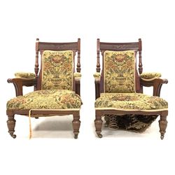 Pair of Victorian mahogany carved open armchairs, with needlework upholstery, raised on turned and reeded front supports with castors, W70cm