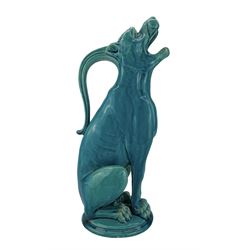 Burmantofts Faience turquoise-glaze ewer modelled as a grotesque hound, seated on all fours, with tilted head and mouth agape in a howl, impressed factory marks beneath, model no. 555 H33.5cm 