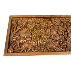 Carved hardwood coffee table, the rectangular top deeply carved depicting village scene with trees and elephants, shaped frieze rails carved with flower heads and foliage