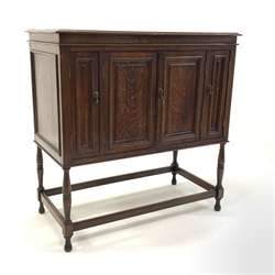 Early 20th century oak gramophone cabinet converted to use a a cupboard, with hinged lid over four doors, raised on turned supports, W96cm, H97cm, d49cm