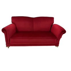Early 20th century drop arm sofa, upholstered crimson fabric with sprung back and seat, raised on brass castors