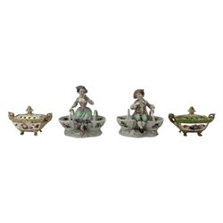 Pair of German porcleian salts in the form of a boy and girl, in 18th century costume, each seated on two baskets, with Augustus Rex marks beneath, H16cm, together with two 19th century porcelain pot pourri vases and covers, with twin scrolled handles, pineapple finials, the bases painted with floral sprays, on four paw supports, in plain and green colourway (2)