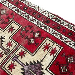Persian crimson ground rug, the field with three pale ground crosses, decorated with geometric motifs, repeating border within guard stripes