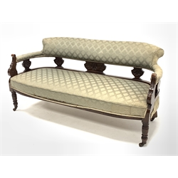  Late Victorian carved walnut framed three seat salon sofa, upholstered in patterned green fabric, raised on turned supports and ceramic castors, W156cm  