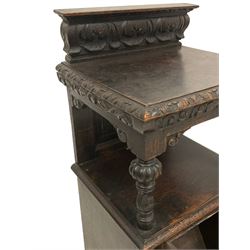 19th century Jacobean Revival heavily carved oak purdonium, raised back carved with acanthus leaves, the moulded and carved edge supported by turned baluster columns uniting the under-tier, the fall-front heavily carved with a floral design flanked by fruit moulded uprights