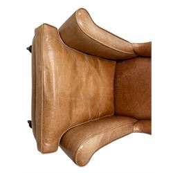 20th century hardwood framed wingback armchair, out swept and rolled arms with loose seat cushion, upholstered in tan leather with piping, on turned oak front supports with brass castors
