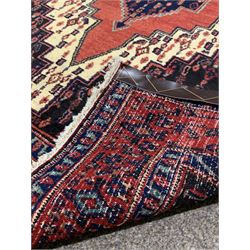 Persian senneh hand knotted red ground rug centred by a geometric medallion and bordered 165cm x 120cm