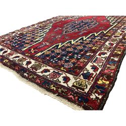 Persian Hamadan red ground rug, the field with a central lozenge medallion surrounded by stylised flower heads, the guarded ivory border decorated with repeating plant motifs