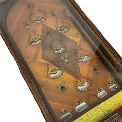 Early 20th century table top bagatelle game 'Uneda', in oak case with glazed top and coin operated mechanism, figured inlaid mahogany surface with painted scores