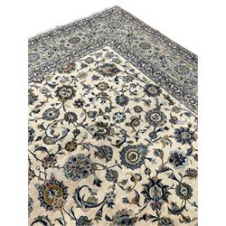 Persian Kashan carpet, ivory ground field decorated with interlacing foliate and stylised plant motifs, scrolling border with repeating flower head motifs, with signature panel