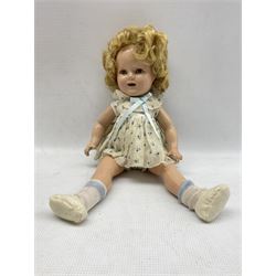 Composition Shirley Temple Reliable doll with applied hair, sleeping eyes and open mouth with teeth, composition body with jointed limbs. In original dress with undergarments, socks and shoes. Some crazing to limbs and face
