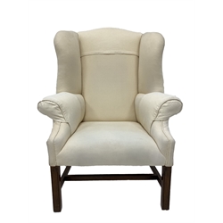 George III style mahogany framed wingback armchair, upholstered in natural linen, with shapely swept wings and arm rests, raised on square moulded front supports with stretchers 