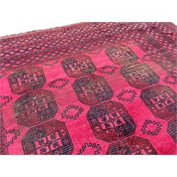 Large old Afghan Bokhara red ground carpet, the field decorated with three rows of seven Gul motifs, multiple borders of repeating geometric designs