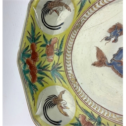 Japanese 18th century decagonal dish in Kakiemon style, Edo, painted with a border pattern of flowers and birds on a yellow ground, the centre with a mythical animal W30cm