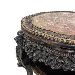 Late 19th to early 20th century carved hardwood jardinière or urn stand, shaped rose marble top enclosed by bead and scrolling foliate carved surround, the frieze rails carved and pierced with flowerheads, on dragon mask carved cabriole supports with ball and claw feet united by under-tier 