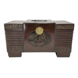 20th century camphor wood storage chest, the projecting central section carved with oriental scenes, hinged lid revealing candle tray, fluting and further carving to each end, raised on block supports  