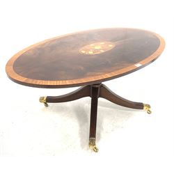Reproduction Regency design mahogany coffee table, the oval satinwood cross banded top centred with floral inlay, over turned column and four splayed supports terminating in hairy paw brass cup castors, 121cm x 69cm, H51cm