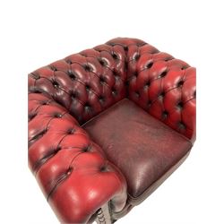 Chesterfield armchair, upholstered in red buttoned back leather, raised on castors 
