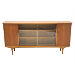 Mid century teak bookcase, two central sliding glass doors enclosing two adjustable shelves, cupboard to each end enclosing more shelves, raised on square tapered supports W165cm, H210cm, D63cm