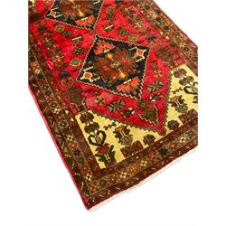 Persian Taleghan red ground rug, the field with two geometric lozenges, surrounded by stylised plant motifs and geometric shapes, the triple band border with repeating flowerheads