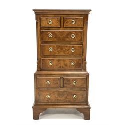 Reproduction figured walnut miniature tallboy, half sawn veneered and cross banded top over two short and three long drawers enclosed by canted and fluted sides, two short and one long drawer under, raised on bracket supports, W38cm, H77cm, D29cm
