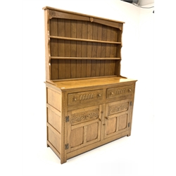 20th century light oak dresser, two height plate rack carved with Yorkshire rose roundels over two drawers and two panelled cupboard doors enclosing shelf, raised on stile supports, W122cm, H169cm, D46cm