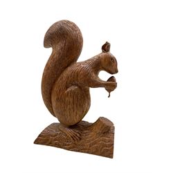 Carved oak model of a Squirrel standing on a branch holding an acorn, signed L. Johnson York EN/ 21177, H23cm