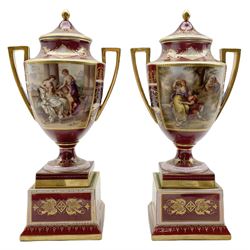 Pair of Vienna style two-handled vases and covers, each reserved with a panel painted by K. Weh with either 'Schmukung der Venus' or 'Rinaldo and Armida', the reverse painted with classical figures against claret, pink and gilt heightened ground, raised on square bases, beehive mark in blue, script titles in black H37.5cm 