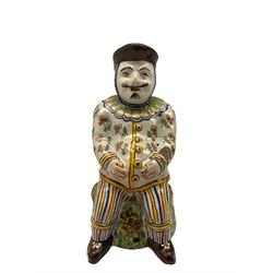 French Faience 'Jacquot', modelled as a seated man with his hands on his stomach, polychrome painted body on sponged base, H17.5cm 