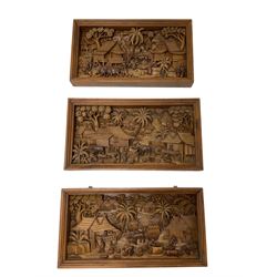 Set of three Chinese hardwood diorama panels, each depicting carved and stained village scenes, framed 