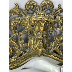 19th century brass girandole mirror, cast with the mask of Dionysus and bordered by pierced scrollwork, issuing two acanthus moulded branches and engraved sconces, with bevelled rectangular arched plate, H44cm, together with a pair of similar rectangular wall mirrors, each with mask crestings and pierced scrollwork borders, H48cm x W25cm (3)