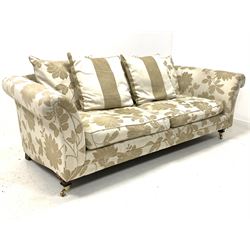 Contemporary three seat sofa, upholstered in floral cream fabric with loose cushions, raised on square tapered front supports with brass cup castors W230cm