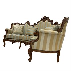 Italian Rococo style carved walnut finish curved three seat wingback sofa, pierced cartouche pediment with swept scrolling, back and seat upholstered in blue and gold fabric with studwork, scrolled hand rail supported by foliate scrolled uprights, joined by pierced cartouche apron with and raised on cabriole supports