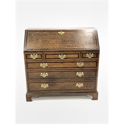 Early 19th century oak and mahogany banded bureau, fall front enclosing interior fitted with small drawers, cupboard and pigeon holes, three frieze drawers above three long graduating drawers, on bracket feet
