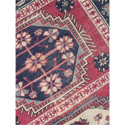 Caucasian red ground rug, the field divided into three panels each with large floral design medallions, repeating guarded border