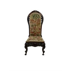 Victorian rosewood nursing chair, the fruit and foliate carved frame and upholstered seat and back, raised on cabriole supports with brass castors  