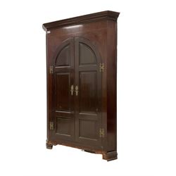 George III mahogany corner cupboard, projecting cornice over banded frieze with ebony and satinwood stringing, fitted with two arched panelled cupboard doors enclosing three shelves over three small drawers