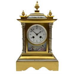 Early 20th century French mantle clock in a brass satin finished case with contrasting silvered detail, canted ogee top surmounted by a central pineapple finial, white enamel dial with Arabic numerals and steel trefoil hands above a porcelain panel depicting cupid and psyche, with flanking silvered Corinthian columns raised on a decoratively shaped rectangular plinth, eight-day countwheel striking movement, striking the hours and half hours on a gong.  With pendulum and key.

