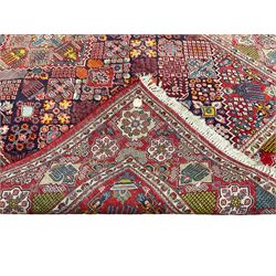 Afghan crimson ground rug, the central lozenge and matching spandrels decorated with candelabra motifs, the indigo field with all-over lozenge decoration of contrasting panels, the guarded border with repeating stylised flower heads and garlands