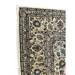 Persian Kashan indigo ground carpet, the field decorated with a central floral medallion surrounded by interconnecting palmette motifs with scrolling branches and leafage, the border decorated with repeating rinceaux patterns and flower heads, guarded by pale blue triple bands
