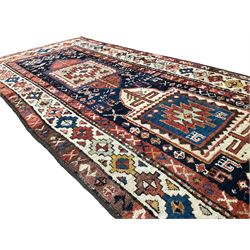 Antique Afghan Kazak red ground rug, the indigo field with two geometric medallions surrounded by stylised animal motifs, the guarded ivory border decorated with repeating geometric patterns