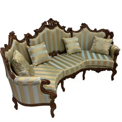 Italian Rococo style carved walnut finish curved three seat wingback sofa, pierced cartouche pediment with swept scrolling, back and seat upholstered in blue and gold fabric with studwork, scrolled hand rail supported by foliate scrolled uprights, joined by pierced cartouche apron with and raised on cabriole supports