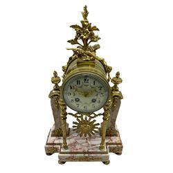 A late 19th century French portico clock on a break front variegated marble base with two conforming marble pillars, with a gilt drum case and eight-day countwheel striking movement striking the hours and half hours on a bell, enamel dial with Arabic numerals and a floral swag, Louis XV pierced gilt hands enclosed within a convex glass and brass bezel, with a visible sunburst pendulum.



