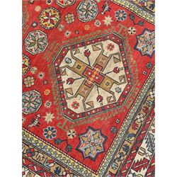 Persian red ground rug, overall geometric design, the field with three main medallions and decorated with stylised motifs, multi-band border decorated with stylised plant motifs