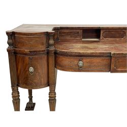 An impressive Irish George III mahogany sideboard, raised back fitted with sliding compartments and two drawers with reed carved balusters and applied cock-beading, fitted with three shallow central drawers and two flanking deep drawers, the central drawer with shaped figured panel, reeded uprights and turned and reeded tapering supports with carved paw feet on moulded blocks, brass lion masks with foliate garland ring handles