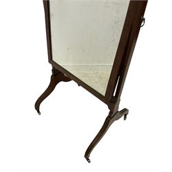 George III mahogany cheval mirror, urn finials over square uprights, the rectangular swing mirror with adjustable brass handles to the side, raised on splayed reeded supports with brass castors
Provenance: From the Estate of the late Dowager Lady St Oswald